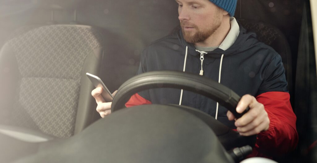 A distracted driver checking their phone while driving.