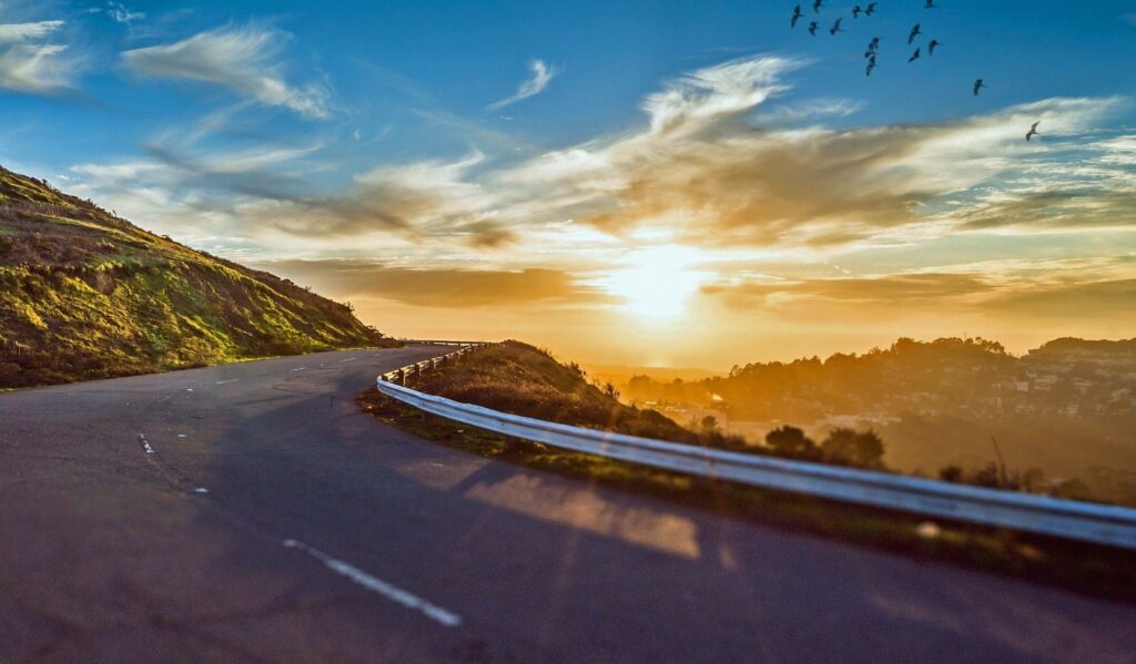 The sun over a cliffside highway.