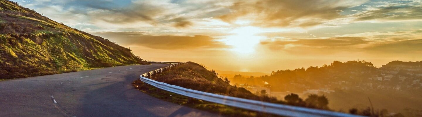 The sun over a cliffside highway.